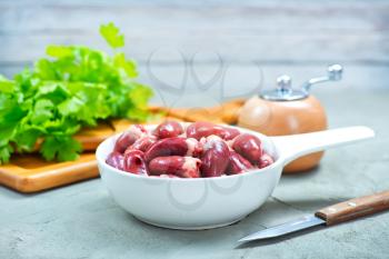 raw chicken hearts in bowl and on a table