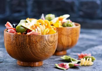 color raw pasta in bowl and on a table
