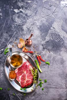 meat with spice on metal plate and on a table