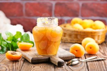 fresh apricot jam in glass bank and on a table