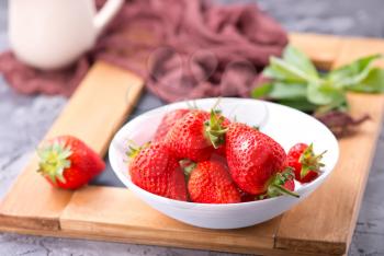 strawberry in bowl and on a table