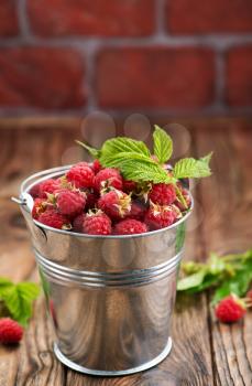 raspberry in metal bowl and on a table