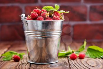 raspberry in metal bowl and on a table