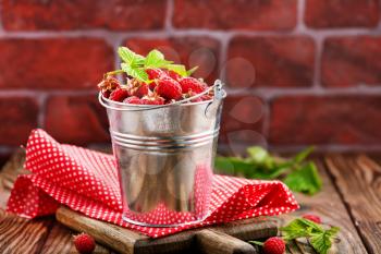 raspberry in metal bowl and on a table