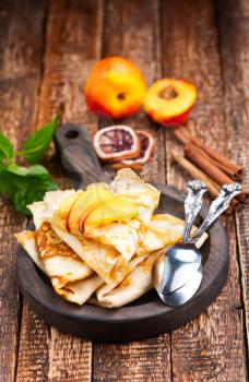 pancake with peach and cinnamon on the wooden board