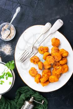 Fried breadcrumb covered chicken popcorn on plate with sauce