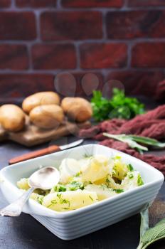 boiled potato in white bowl and on a table