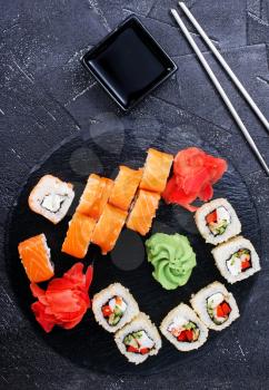 Japanese sushi on a rustic dark background. Sushi rolls and ginger, wasabi, soy sauce. 