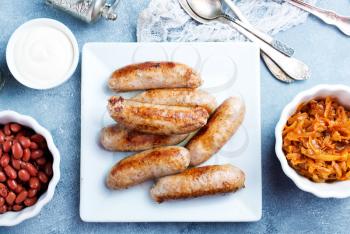 sausages on white plate, fried sausages with sauce