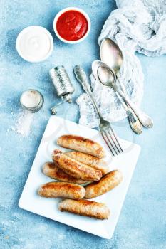 sausages on white plate, fried sausages with sauce