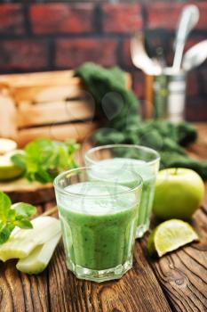 Glass of green vegetable smoothie. Green vegetable smoothie and ingredients: celery avocado cucumber kiwi apple banana lemon and herbs