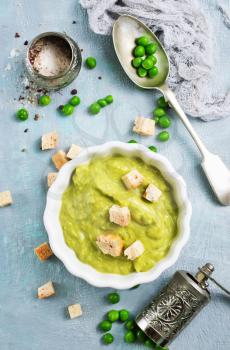 Mashed green peas and olive oil in a ceramic bowl on a table. Healthy vegetarian food