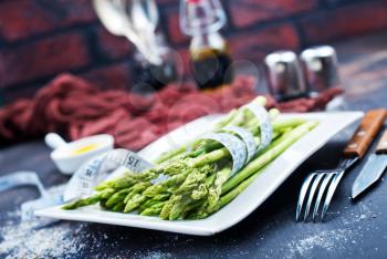 green asparagus on white plate and on a table