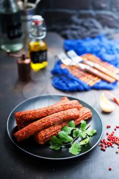 sausages on black plate, smoked sausages, sausages with spice