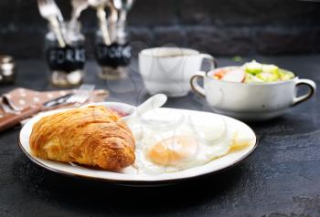 breakfast on a table, fried eggs and croissant
