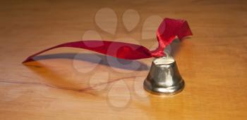 Bell with a red ribbon on a wooden background