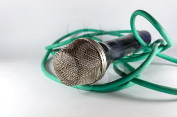 Old microphone with green cable on light background