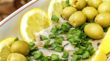Herring fillet salad with yellow olives lemons and green onions