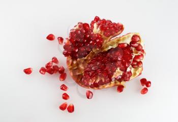 Part of delicious juicy ripe pomegranate and pomegranate seeds scattered around. Studio shot. Top view. 