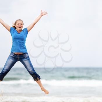 Happy young blonde woman jumping outdoors. Jumping girl. Selective focus on the model. Space for text.