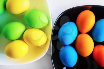 Bright colored Easter eggs in a black and white dishes. Top view.