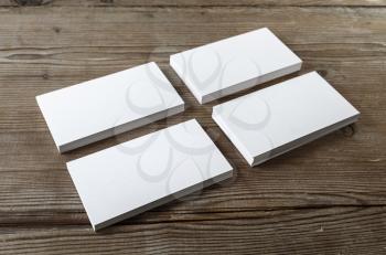Four stacks of blank business cards on a dark wooden background. Mockup for branding identity. Shallow depth of field.