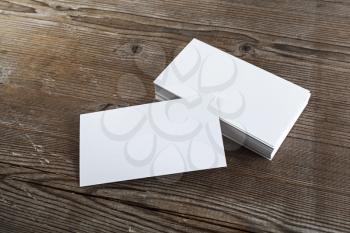 Blank white business cards on a dark wooden background. Mockup for branding identity. Shallow depth of field.