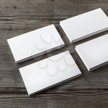 Set of blank white business cards on a dark wooden background. Template for branding identity. Shallow depth of field.