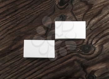 Blank white business cards on dark wooden table background. Mock-up for branding identity. Template for your design. Top view.