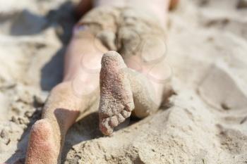 Child's feet in the sand on the beach. Shallow depth of field. Selective focus.