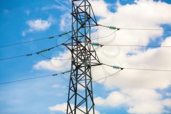 High-voltage electricity pylon against blue sky. Electric power transmission. High voltage wires.