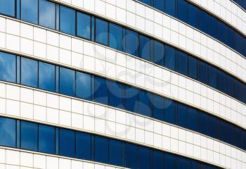 Facade of a modern building of steel and glass. Modern industrial architecture. Reflection of blue sky with clouds in the windows.