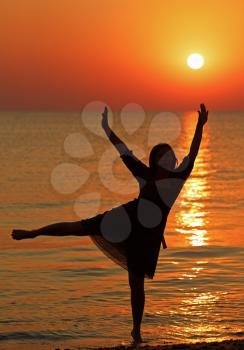 Girl dancing on the background of sunrise over the sea. Shallow depth of field.