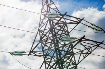 Close-up of high voltage tower. Electricity pylon against cloudy sky background. 