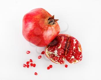 Ripe pomegranate and its half with reflection on a light background. Studio shot. Top view.