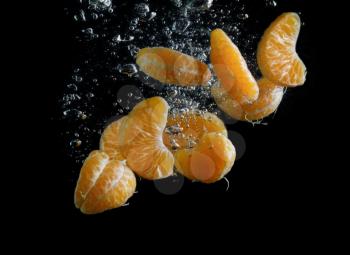 Dalkey delicious mandarin falling in water with air bubbles. Photo on black background.