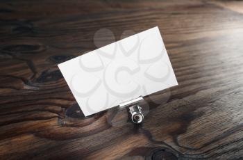 Blank business card and paper clip with soft shadow on dark brown wooden background. Blank template for branding identity for design presentations and portfolios.