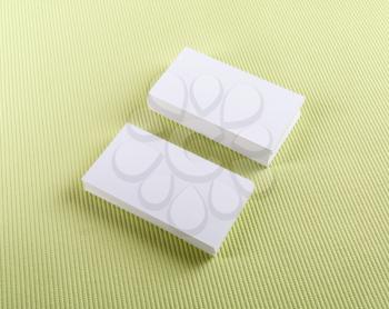 Blank business cards with soft shadows on green background.