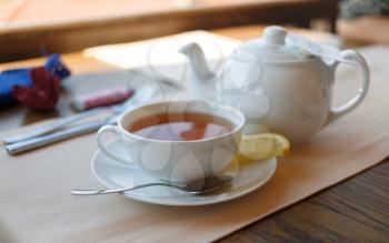 Cup of tea with lemon and teapot. Shallow depth of field.