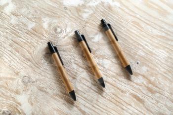 Three mechanical ballpoint pens on the wooden background. Template for design presentations and portfolios. Top view.