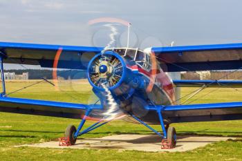 Airplane with the rotating propeller. Old retro blue plane close-up. Front view, with the side of the fuselage.