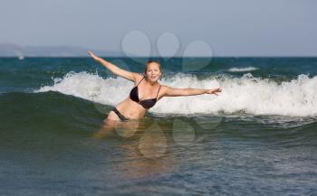 Smiling beautiful woman on the background of sea wave on a bright sunny day.