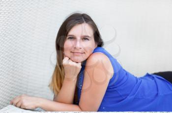 Photo of pretty young woman with long hair in a blue t-shirt. Portrait of a girl lying down and propping face in her hands closeup. Shallow depth of field. Focus on the model's face. 