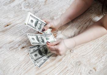 Woman hands with dollars on a wooden background. Cash in hands. Money in hands. Fake money. Shallow depth of field. Selective focus.