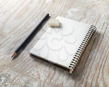 Photo of blank notepaper with pencil and eraser on light wooden background. Template for graphic designers portfolios. Mock-up for branding identity.