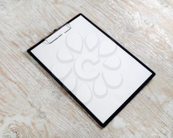 Photo of clipboard with a blank sheet of paper on light wooden background with plenty of copy space. Blank template for design presentations and portfolios.