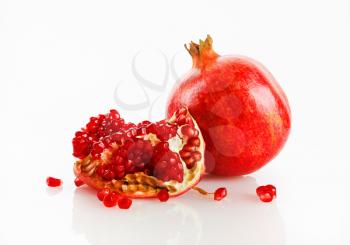 Ripe tasty fresh red pomegranate fruit and its grain with reflection on a light background. Studio shot.