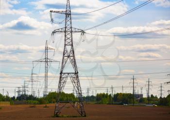 Electricity transmission pylons through field. High voltage towers.