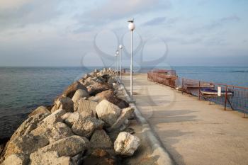 Breakwater extending in the sea. Pierce with lampposts. Calm summer day on the coast of the Black Sea.