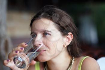 Pretty young woman drinking pure water from a transparent glass beaker. Selective focus.